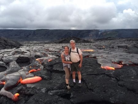 couple standing on lava bed with hot ash surrounding them.