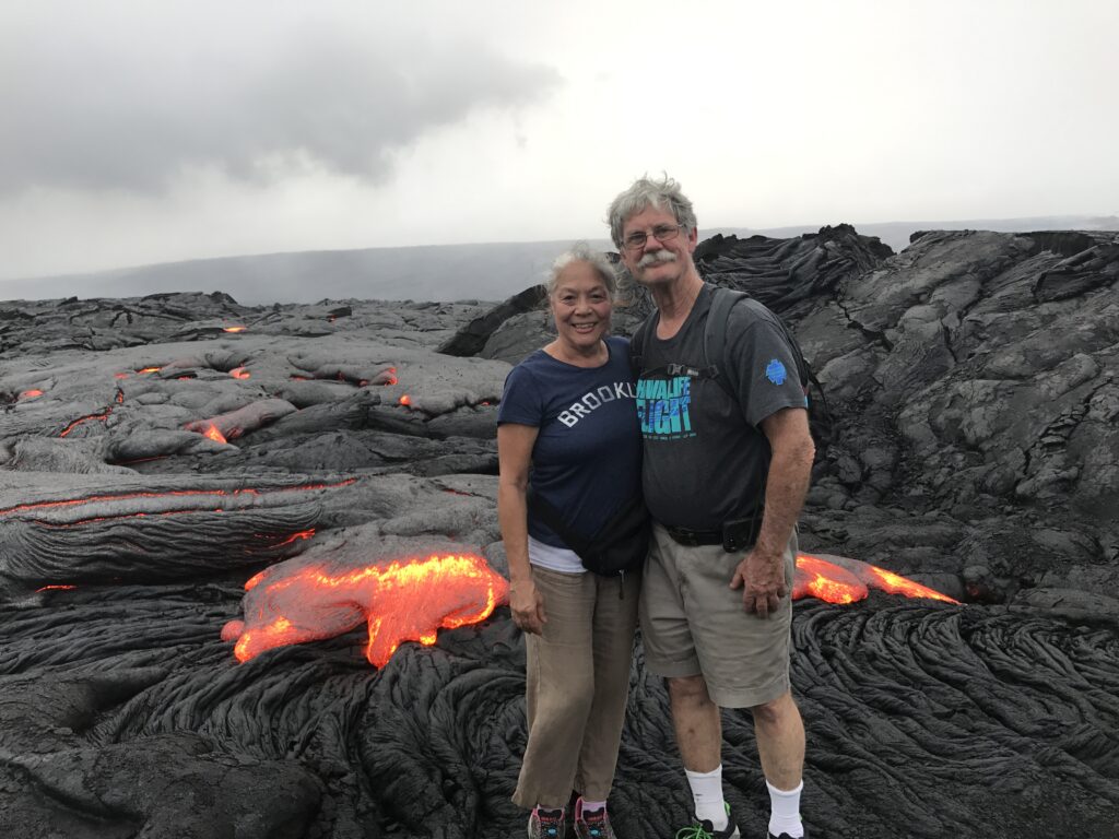 couple standing on lava bed with hot ash surrounding them.